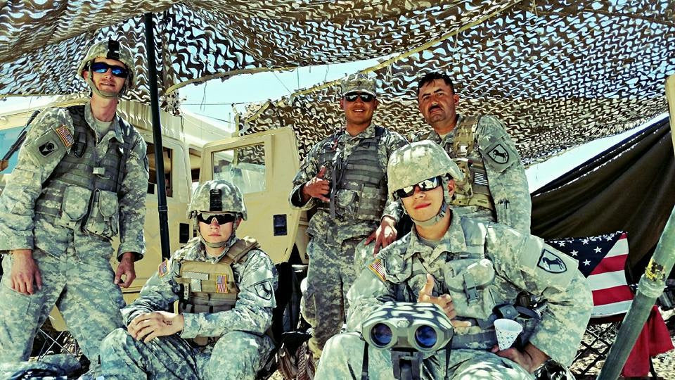 Group of soldiers in military uniforms with camouflage coverings in the background